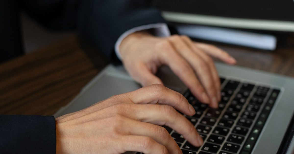 Hands typing on a laptop keyboard at a desk