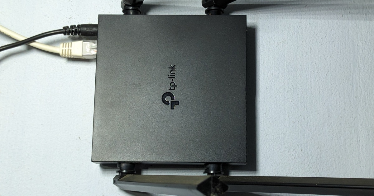 A black TP-Link Archer router seen from above, with its antennas raised and network cables plugged in