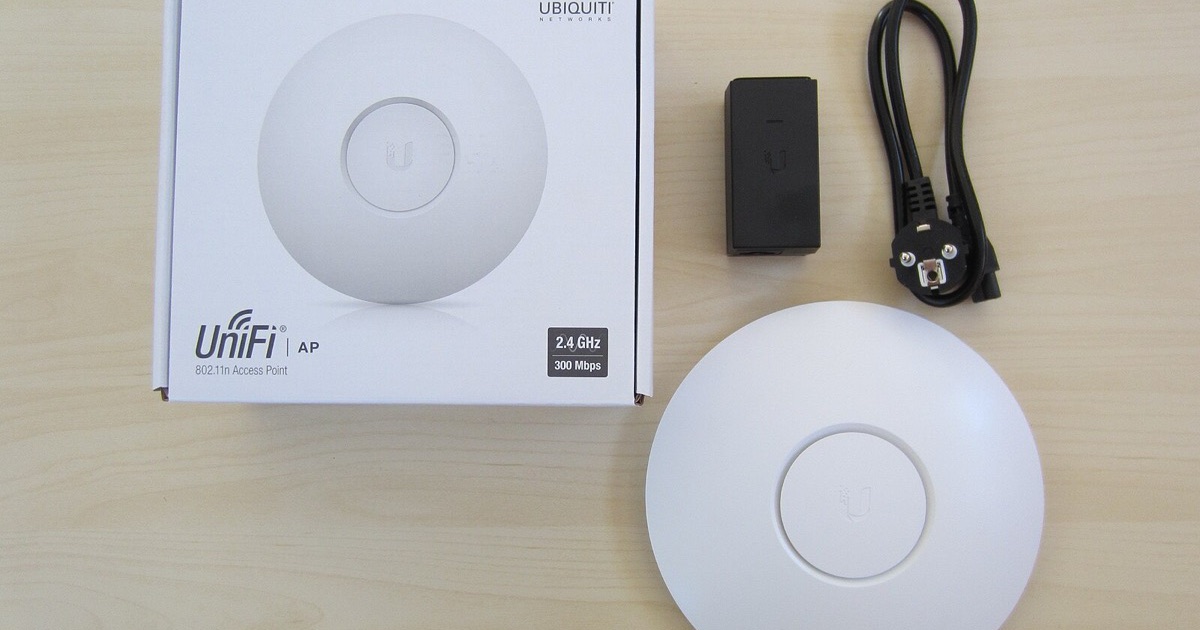 A Ubiquiti UniFi access point next to its box, its PoE adapter and a power cable